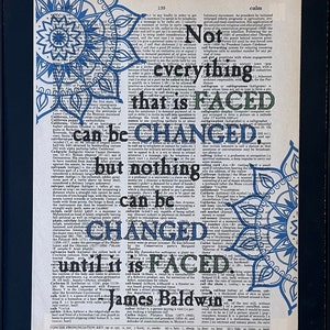 Not everything that is faced can be changed, but nothing can be changed until it is faced. James Baldwin. Printed on a page from a dictionary with images of mandalas.