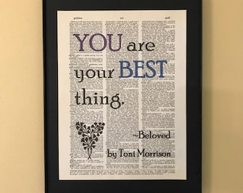 May include: A framed print of a dictionary page with the words "You are your best thing." in colourful text. The quote is attributed to Toni Morrison and the book title "Beloved" is also included.