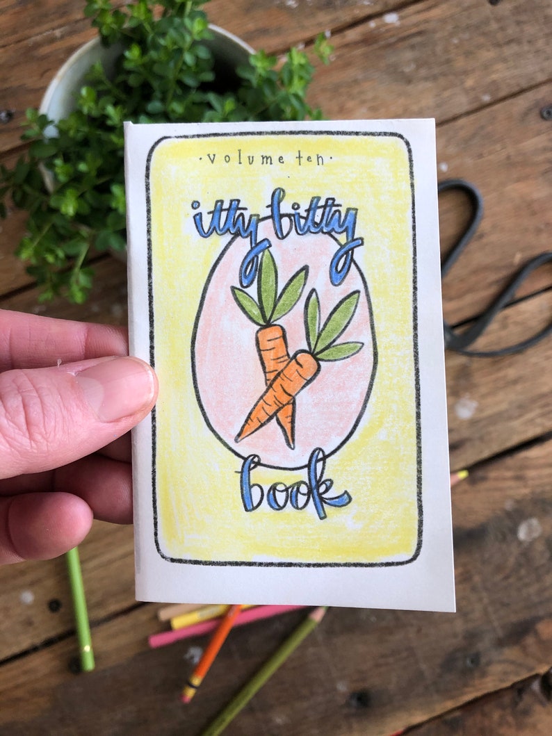 May include: A small, yellow book with the title "itty bitty book" and the words "Volume ten."  The book has a drawing of two carrots with green leaves inside a pink oval.
