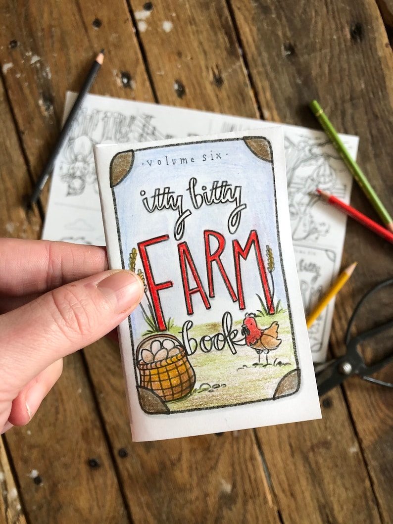 May include: A small, blue and white book with the title "itty bitty FARM book" and the text "volume six." The book cover features a red rooster and a basket of eggs.