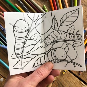 May include: A black and white coloring book page featuring three caterpillars on leaves. The caterpillars have striped bodies and cute faces.
