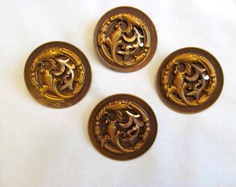 May include: Four antique brass buttons with a detailed floral design. Each button features a raised, gold-colored floral pattern set against a dark brown background. The buttons are round and have a vintage aesthetic.