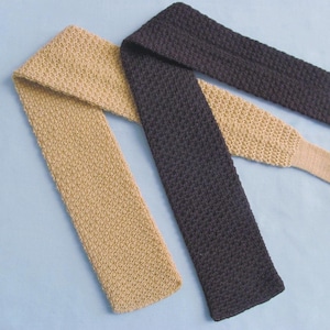 May include: Two knitted neckties in the image. One is a light tan color, and the other is a dark charcoal gray. Both ties have a textured, woven appearance. The ties are displayed on a light blue background.