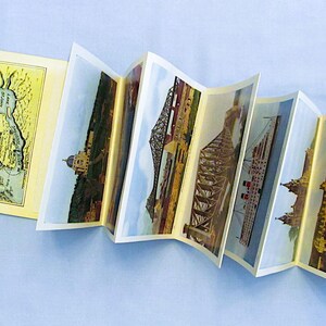 May include: A vintage postcard booklet featuring images of a bridge, a ship, and a city skyline. The booklet is open to reveal the different postcards.