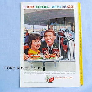 May include: A vintage October 1958 National Geographic magazine back cover featuring a Coca-Cola advertisement. The ad shows a smiling couple in a car with food trays, text reading BE REALLY REFRESHED...DRIVE-IN FOR COKE! and SIGN OF GOOD TASTE.