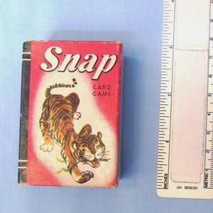 May include: A rectangular Snap card game box with a red background and a tiger illustration. The box features the text Snap and Card Game. A white ruler is positioned to the right, showing the box height is approximately 3.5 inches.