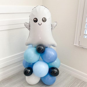 May include: A white ghost balloon with a smiling face, surrounded by blue and white balloons, and black balloons.