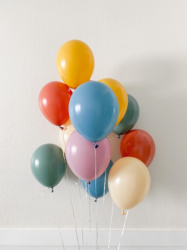 May include: A bunch of colorful balloons in shades of blue, green, yellow, orange, and pink. The balloons are tied together with white ribbons.