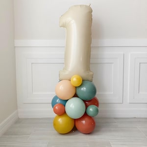 May include: A large beige number one balloon with a cluster of smaller balloons in various colors, including peach, yellow, teal, and red, at the base.