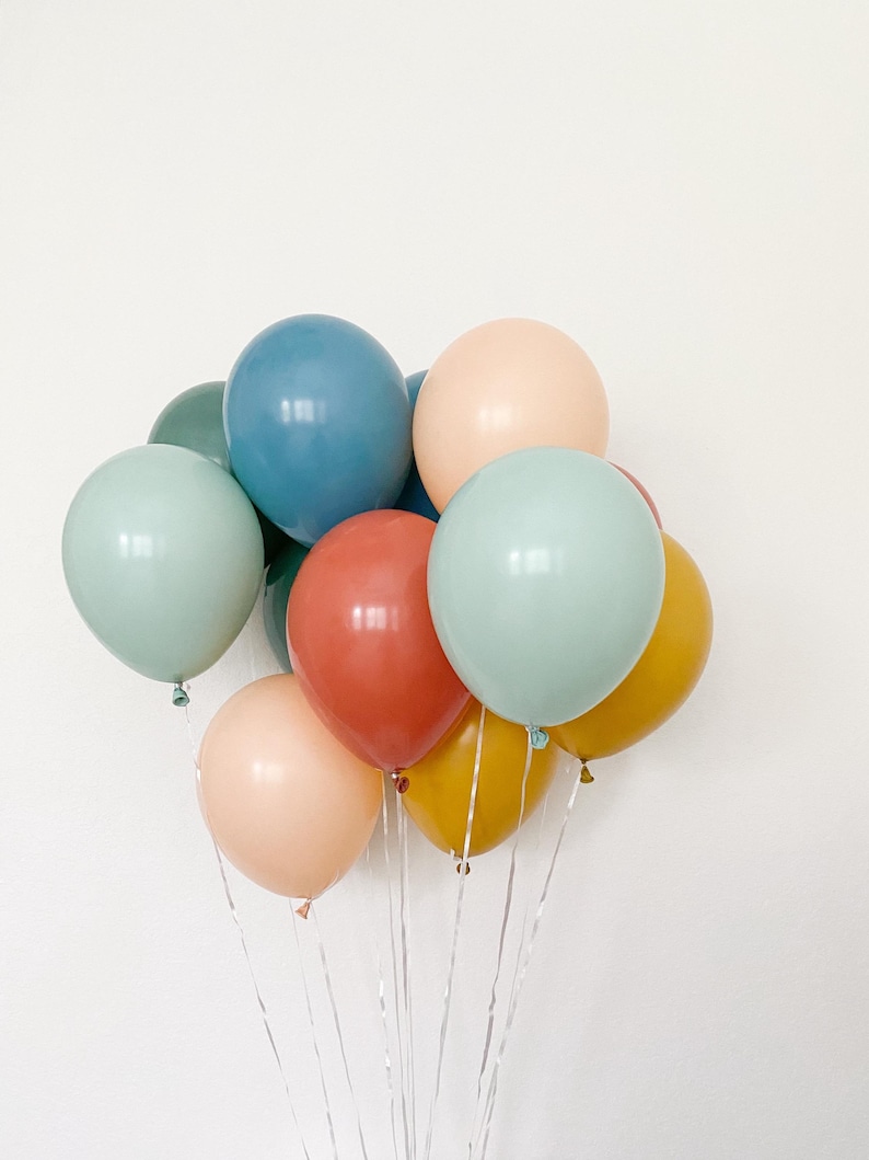 May include: A bunch of pastel colored balloons in shades of blue, green, peach, and yellow. The balloons are tied together with clear ribbon.