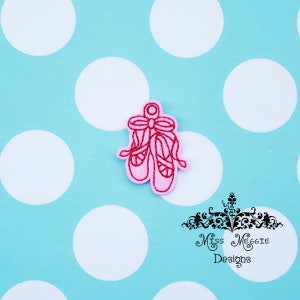 May include: Pink felt ballerina shoes with a red ribbon, embroidered on a white background.