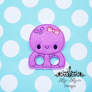 May include: Purple felt finger puppet of an octopus with a pink bow. The octopus has a smiling face and four tentacles with finger holes.