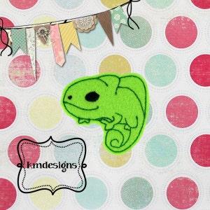 May include: Green felt applique of a chameleon with a black eye. The applique is on a white background with colorful polka dots.