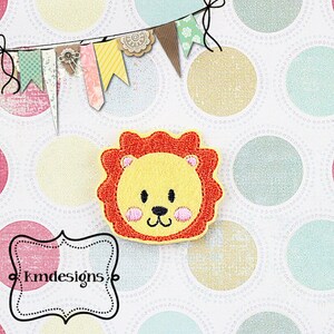 May include: A yellow lion face with a red mane, pink cheeks, and black eyes. The lion is embroidered on a white background with a polka dot pattern.