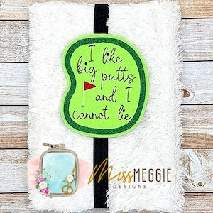 Peut inclure: Un bandeau de golf blanc et duveteux avec une bande noire. Le bandeau présente un patch vert avec le texte "I like big putts and I cannot lie" et un petit drapeau rouge. Le logo Miss Meggie Designs est également visible.
