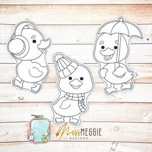 May include: Three outline drawings of ducklings, each with a unique accessory. One duckling wears headphones, another a winter hat and scarf, and the third holds an umbrella. The text "Miss Meggie Designs" is visible.