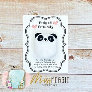 Può includere: Un biglietto bianco con testo nero che dice "Fidget Friends" con due cuori rosa. Il biglietto ha un bordo nero e un panda bianco con orecchie e occhi neri al centro. Il testo sotto il panda dice "Feeling Nervous or having a fidgety day? Fidget friends are with you every step of the way." La parte inferiore del biglietto dice "MissMEGGIE DESIGNS".