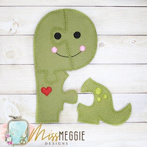 May include: Green felt dinosaur puzzle with a red heart on the body and yellow spots on the tail. The dinosaur is made of five pieces.