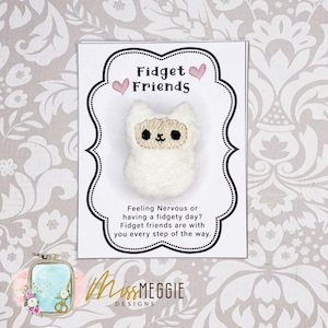 May include: A white llama-shaped fidget toy on a card with the text "Fidget Friends." The card has a decorative border and the text "Feeling Nervous or having a fidgety day? Fidget friends are with you every step of the way."