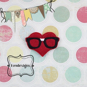 Puede incluir: Corazón de fieltro rojo con gafas de fieltro negro. El corazón está sobre un fondo blanco con un patrón de lunares de colores.