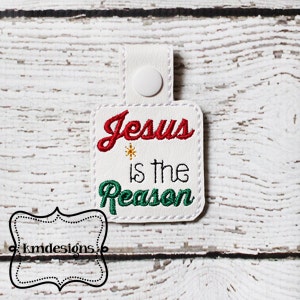 May include: White fabric key chain with a red and green embroidered design that says "Jesus is the Reason".