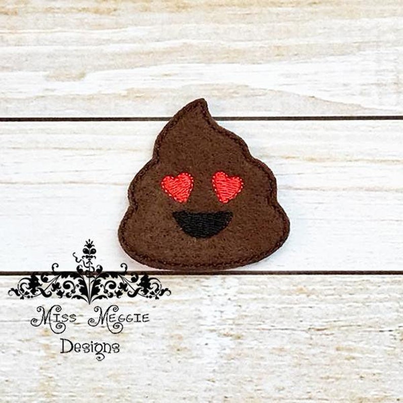 May include: Brown felt emoji with a smiling face and heart eyes. The emoji is shaped like a pile of poop.