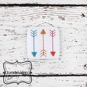 May include: Three embroidered arrows in a square shape. The arrows are teal, orange, and red.