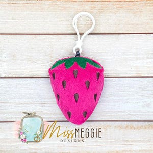 May include: A plush strawberry keychain with a green stem and leaves. The strawberry is pink and has a white loop for attaching to a bag or keys.