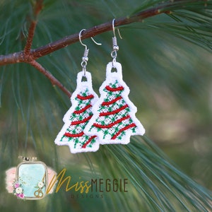May include: A pair of silver earrings with white, red, and green embroidered Christmas tree designs.