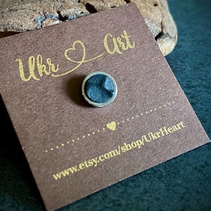 May include: A small, round, dark blue pin with a silver border is displayed on a brown card. The card has gold text that reads "Ukr Art" and "UkrHeart". The Etsy shop URL is also visible.