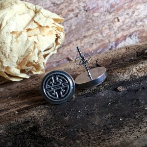 May include: A pair of silver stud earrings with a black circular design featuring a traditional Chinese knot symbol.