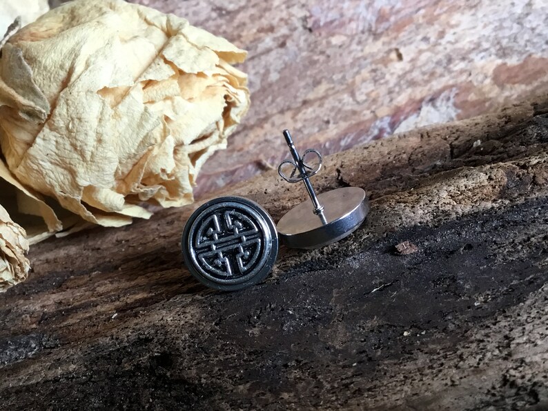 May include: A pair of silver stud earrings with a black circular design featuring a traditional Chinese knot symbol.