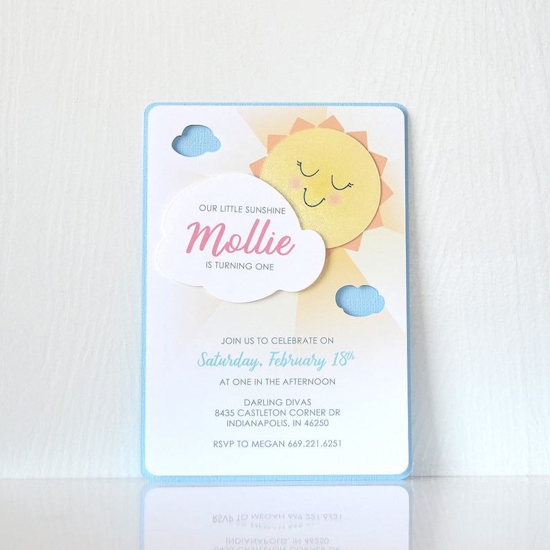 May include: A blue and yellow birthday invitation with a sun and clouds. The text reads "Our little sunshine Mollie is turning one. Join us to celebrate on Saturday, February 18th at one in the afternoon. Darling Divas 8435 Castleton Corner Dr Indianapolis, IN 46250 RSVP to Megan 669.221.6251"
