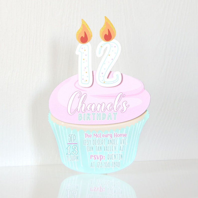 May include: A light blue and pink cupcake with a white number 12 on top. The cupcake has two lit candles with orange flames. The text "Chanel's Birthday" is written on the cupcake. The invitation includes the date, time, location, and RSVP information.