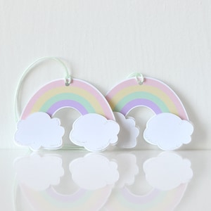 Pode incluir: Duas etiquetas de presente arco-&iacute;ris pastel com nuvens brancas. Cada etiqueta tem um furo perfurado na parte superior para uma corda ou fita.