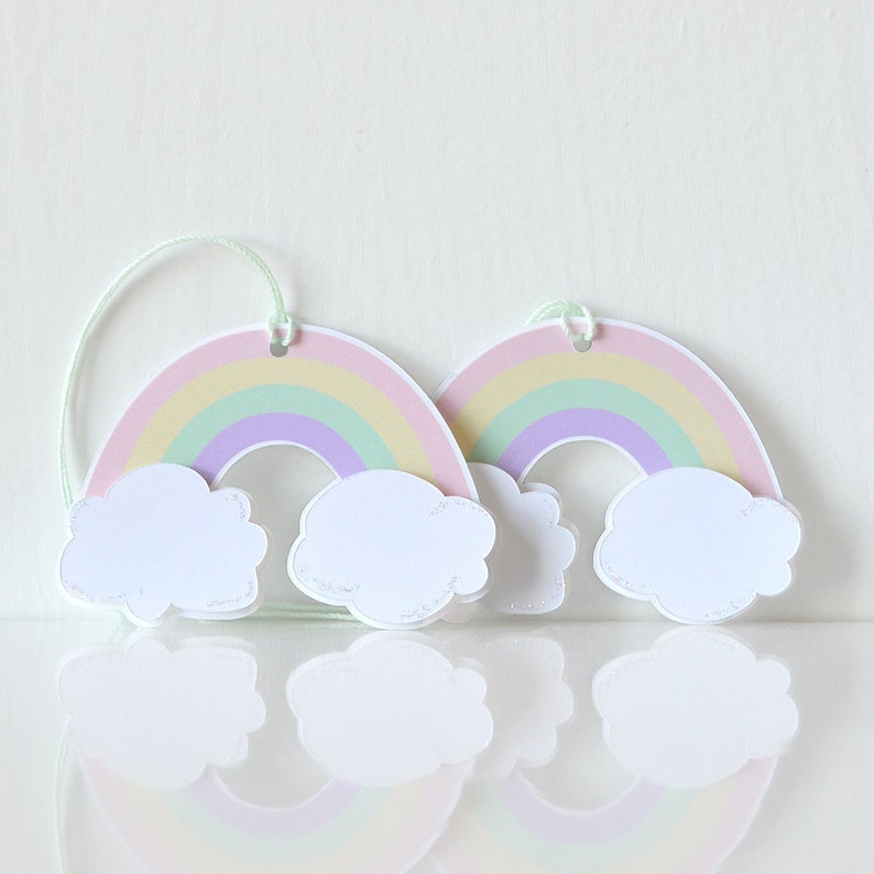 Pode incluir: Duas etiquetas de presente arco-&iacute;ris pastel com nuvens brancas. Cada etiqueta tem um furo perfurado na parte superior para uma corda ou fita.