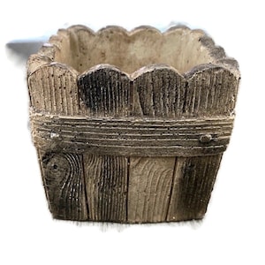Op de afbeelding: Een vierkante, bruin en beige plantenbak met een houtstructuur. De plantenbak heeft een gegolfde bovenrand en een verhoogde rand.