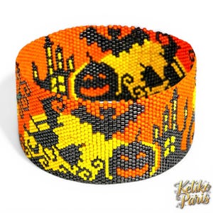 May include: A beaded cuff bracelet with a Halloween theme. The bracelet features orange, black, and yellow beads arranged to depict bats, jack-o'-lanterns, and a haunted house. The bracelet is cylindrical and has a repeating pattern.