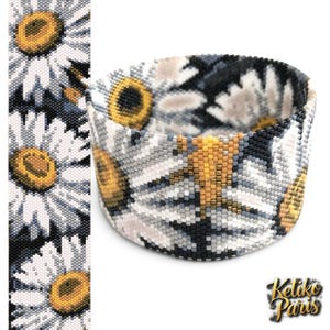 May include: A wide cuff bracelet crafted from small beads featuring a repeating pattern of white daisy flowers with yellow centres against a dark grey and black background. The text Ketiko Paris is visible in the bottom right corner of the image.