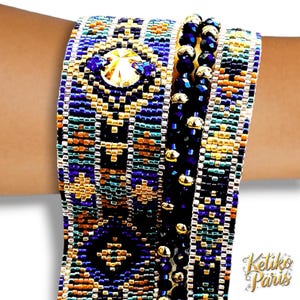 May include: Close-up of a beaded bracelet with a geometric pattern in blue, gold, orange, and black. The bracelet features a large, faceted crystal and smaller blue gems. A second bracelet with black beads and gold accents is also visible.