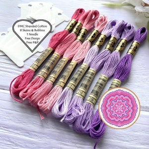 May include: Eight skeins of DMC stranded cotton embroidery floss in shades of pink and purple. The floss is arranged in a gradient from pink to purple. The skeins are labelled with their DMC numbers: 602, 603, 504, 211, 210, and 209. A small cross-stitch pattern of a pink flower is also included.