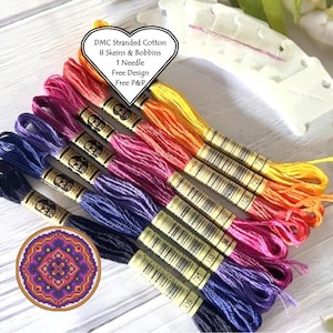 May include: Eight skeins of DMC stranded cotton embroidery floss in a rainbow gradient of colors, from yellow to purple. The floss is wrapped around white bobbins and labeled with DMC numbers. A small, round cross-stitch pattern is also included.