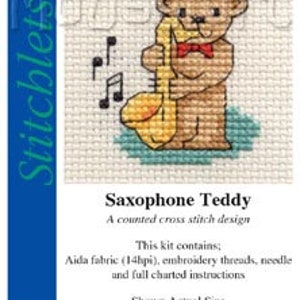 May include: A counted cross stitch kit featuring a brown teddy bear playing a yellow saxophone. The kit includes Aida fabric, embroidery threads, a needle, and full charted instructions. The design is titled "Saxophone Teddy" and is from Mouseloft.