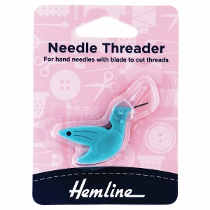 May include: A teal plastic needle threader in a clear plastic package. The package is pink with white sewing-themed illustrations and the words "Needle Threader" and "Hemline". The threader is shaped like a bird.