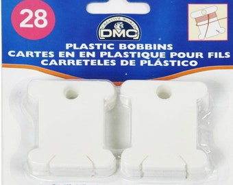 May include: A package of 28 white plastic bobbins for winding thread. The package is labeled "Plastic Bobbins" and "Cartes en en plastique pour fils Carreteles de plástico".
