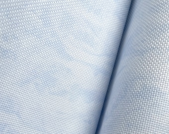 May include: Close-up of a light blue fabric with a textured weave. The fabric is folded in half, showing the texture on both sides.