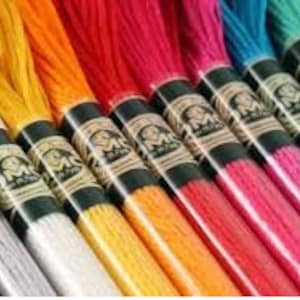Puede incluir: Surtido de carretes de hilo de bordar DMC en varios colores, incluyendo gris, plateado, amarillo, naranja, rojo, rosa, azul, turquesa y verde.