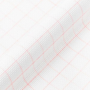 May include: White fabric with a pink grid pattern. The fabric is folded and has a textured surface.