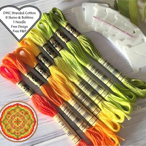 May include: Eight skeins of DMC stranded cotton embroidery floss in shades of orange, yellow, and green. The floss is wound on bobbins and arranged in a rainbow gradient. The image also includes a needle and a small embroidery hoop with a colourful mandala design.