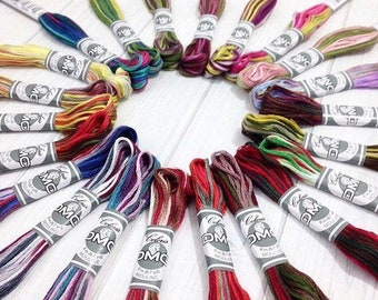 May include: A collection of 20 DMC embroidery floss spools arranged in a circle. The spools are wrapped in various colors of thread, including red, green, blue, and yellow.